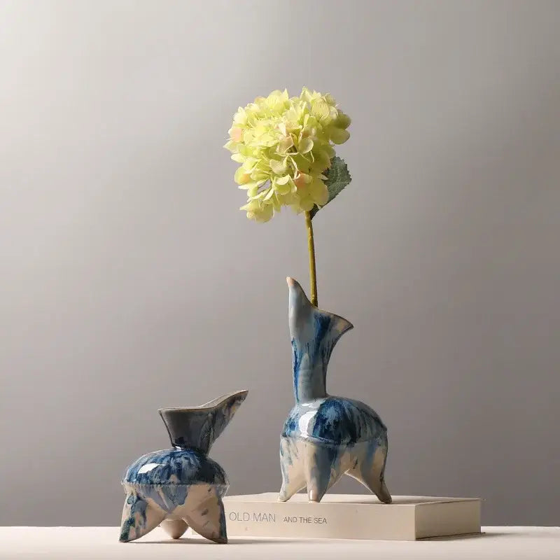 Blue and white ceramic vase with irregular ink pattern shaped like a three-legged animal holding a pale yellow hydrangea bloom