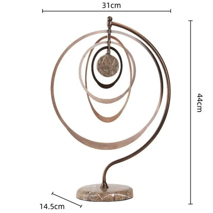 Abstract bronze geometric sphere pendant sculpture with concentric rings and textured centerpiece on marble base for decor