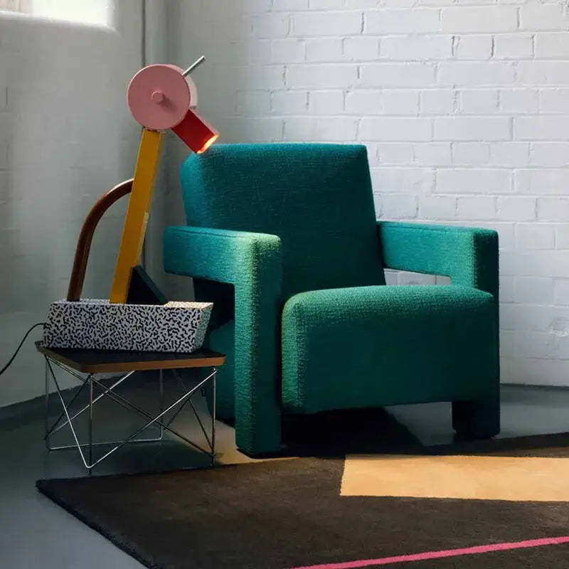Teal upholstered armchair with modern blocky design paired with abstract duck led colorful art deco table lamp