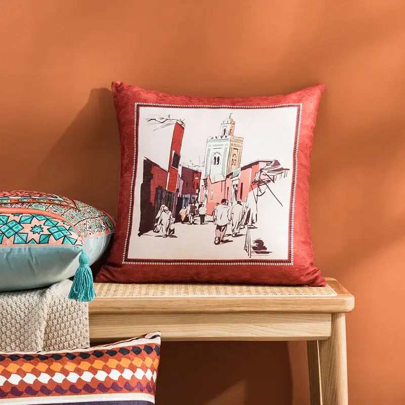 Red velvet cushion cover with framed moroccan street scene illustration featuring coral and teal abstract geometric decorbites design
