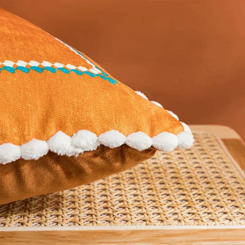 Orange cushion cover with white pom-pom trim and turquoise abstract geometric printed decorbites pattern for living room decor