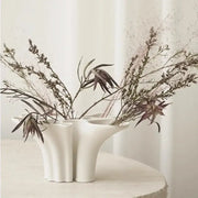White ceramic abstract geometry vase with fluted sides and triple openings holding dried botanicals for living room decor