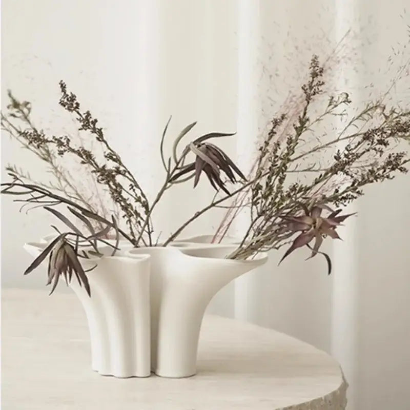 White ceramic abstract geometry vase with fluted sides and triple openings holding dried botanicals for living room decor