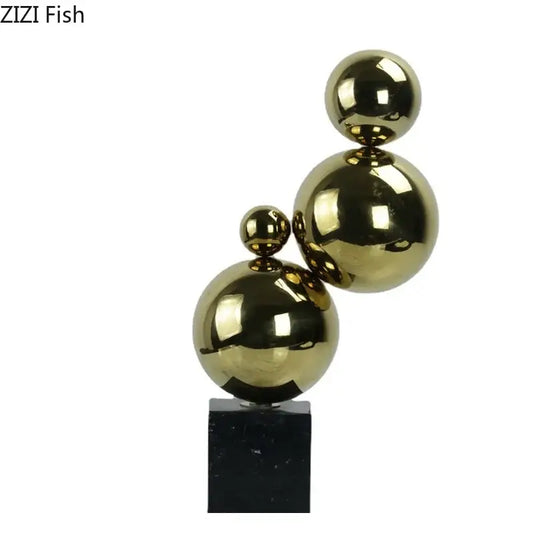 Shiny gold metallic spheres in an abstract golden balls geometric metal sculpture on a black marble base for decorbites decor