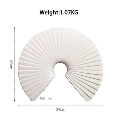 White ceramic fan-shaped decorative object with radial ridges and central hole for abstract gold resin statue decor