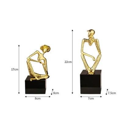 Two gold-toned abstract human hat thinker figures seated on black bases for decorbites golden hat living room decor