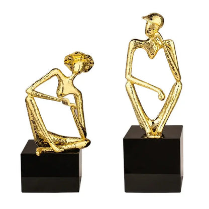 Two abstract golden hat thinker figurines seated on black square bases for living room decorbites golden hat decor