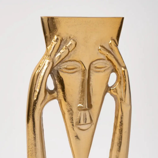 Golden metallic abstract sculpture of a masked figure with hands framing its head for living room decor