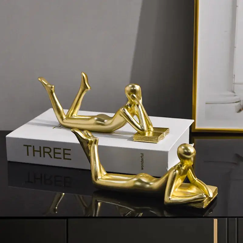 Golden metallic abstract thinker reader man figurines reclining on books ideal for living room decor