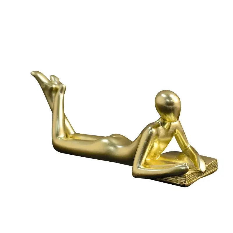 Golden metallic thinker reader man figurine reclining and reading an open book for living room decor