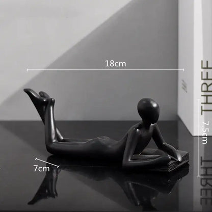 Black glossy resin figurine of a minimalist thinker reader man reclining reading for living room decor