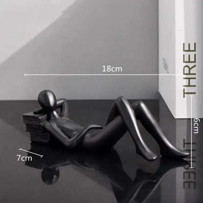 Black glossy resin figurine of a reclining human form on books as golden thinker reader man living room decor