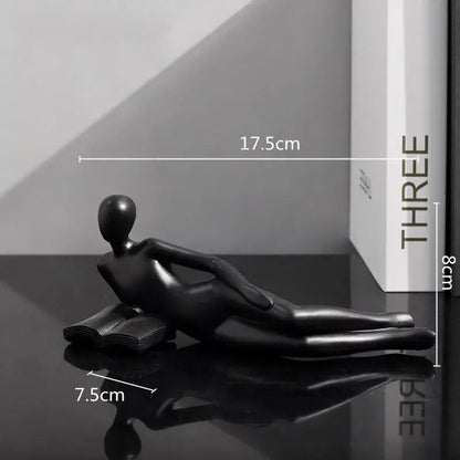 Black glossy resin figurine of a reclining human form on an open book for abstract golden thinker reader decor