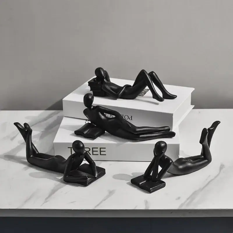 Black glossy resin figurines of abstract human forms in relaxed poses for golden thinker reader living room decor