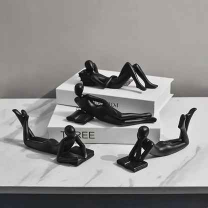 Black glossy resin figurines of abstract human forms in relaxed poses for golden thinker reader living room decor