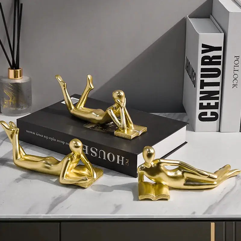 Golden thinker reader man figurines in glossy abstract human forms with relaxed reading poses for living room decor