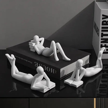 White ceramic minimalist human figurines in reading poses for abstract golden thinker reader man living room decor