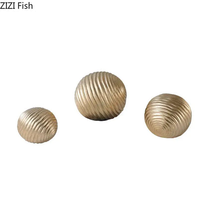 Set of three gold-toned ribbed metal decorative orbs for living room featuring an abstract golden wave ball design