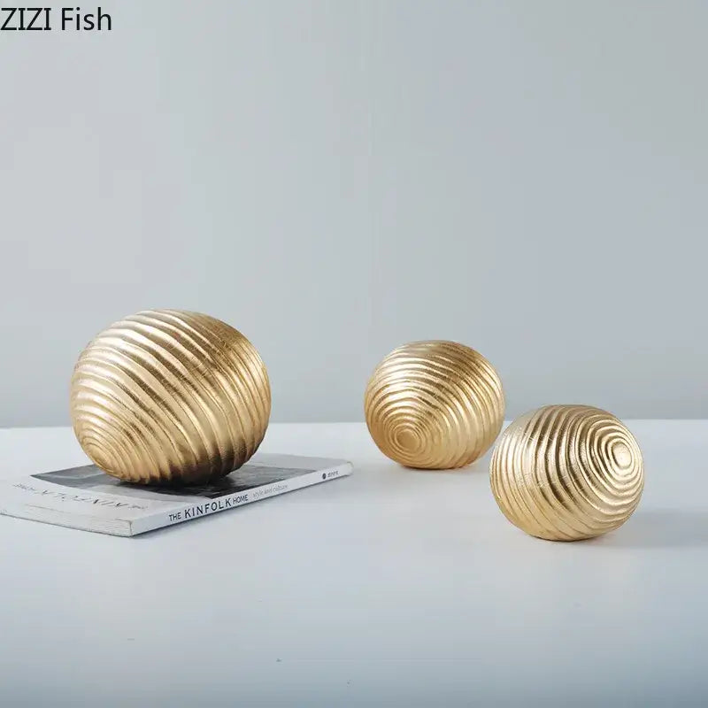 Three golden ribbed spherical decorative orbs with metallic finish as abstract golden wave ball metal decor for living room