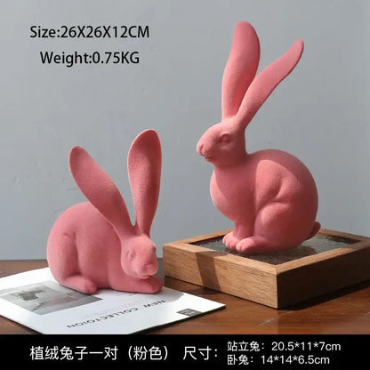 A pair of soft pink plush rabbit figurines with velvety fabric complementing abstract rabbit resin decor art