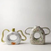 Two ceramic vases with abstract handle ceramic design and hand-painted floral accents in muted green and red decorbites abstract handle