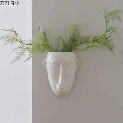 White ceramic vase wall decor featuring an abstract human face planter with green ferns by decorbites abstract human face