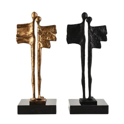 Two abstract iron cast couple statues in gold and black with wing-like features on rectangular bases for living room decorbites abstract iron decor