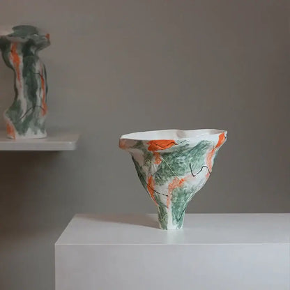 A white ceramic vase with a flared irregular rim featuring an abstract irregular pattern of green and orange for living room decor