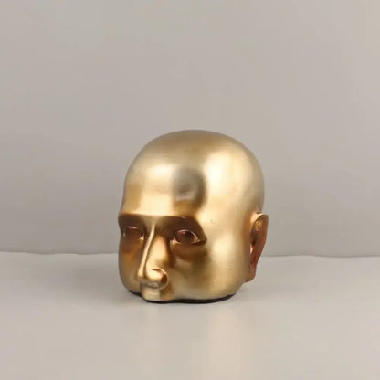 Golden metallic head half sculpture with smooth reflective surface and minimalist features for home decor by decorbites