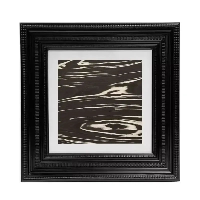 Black ornate picture frame holding decorbites abstract modern wall art with swirling white lines on dark brown background