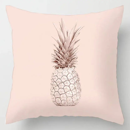 A soft pink cushion cover with a stylized pineapple and geometric leaves print in muted silver and beige tones