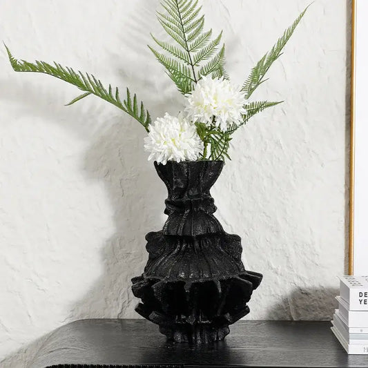 Black ruffled ceramic abstract pleated gear vase with white flowers and green ferns for living room decor
