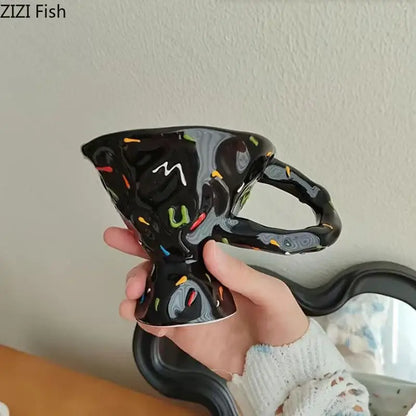 Black ceramic mug with glossy finish featuring color decorbites colorful icing splatters and white cursive m decoration