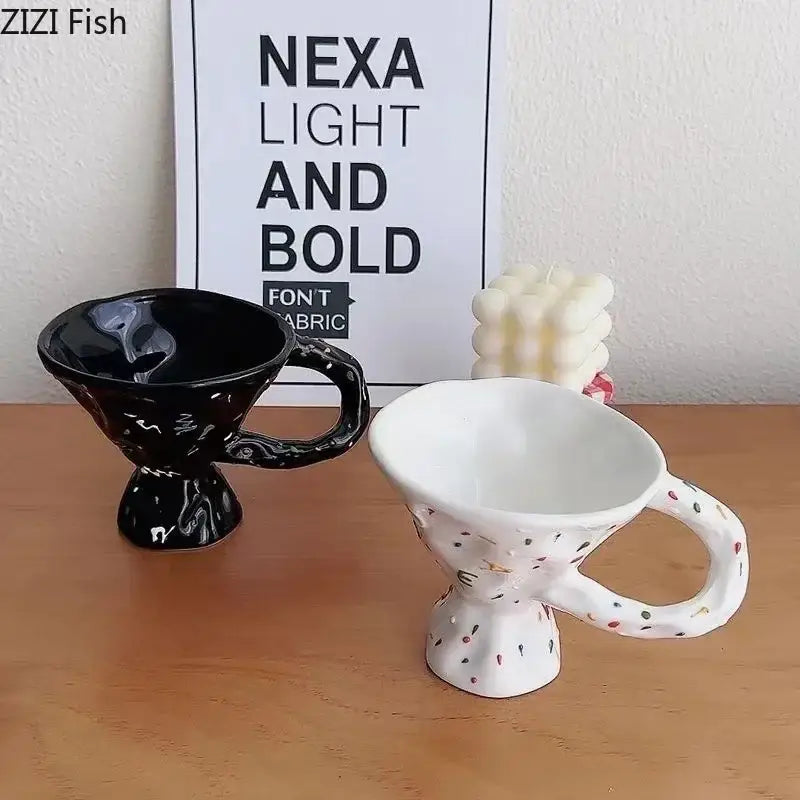 Two decorative ceramic mugs with unique sculpted design in glossy black and white speckled colors on wooden surface