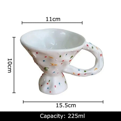 A white ceramic mug with a textured speckled design and colorful confetti dots for decorative ceramic mug decorbites colorful icing