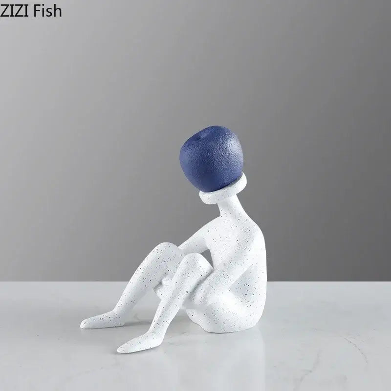 Abstract thinker resin figurine in white speckled with blue spherical head in an abstract seated pose for living room decor