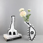 White ceramic vase with black geometric eye pattern and abstract fish design for living room decor