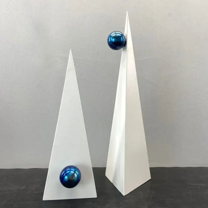 Two minimalist white geometric triangle sculptures topped with glossy blue spheres for decorbites geometric triangle decor