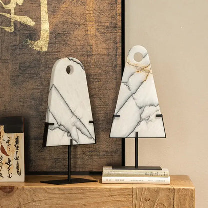 Two white marble cutting boards with natural veining and black metal stands complementing decorbites abstract jade pendant