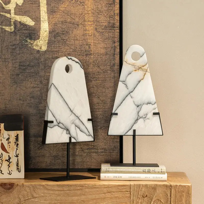 Two white marble cutting boards with natural veining and black metal stands complementing decorbites abstract jade pendant