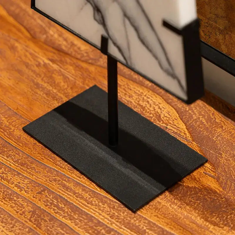 Black metal display stand holding white marble sculpture with black veining for abstract jade pendant decorbites decor