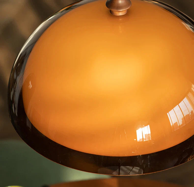 Acrylic pendant light with a sleek amber glass dome, polished chrome rim, and brass finial in dark wood lampshade style