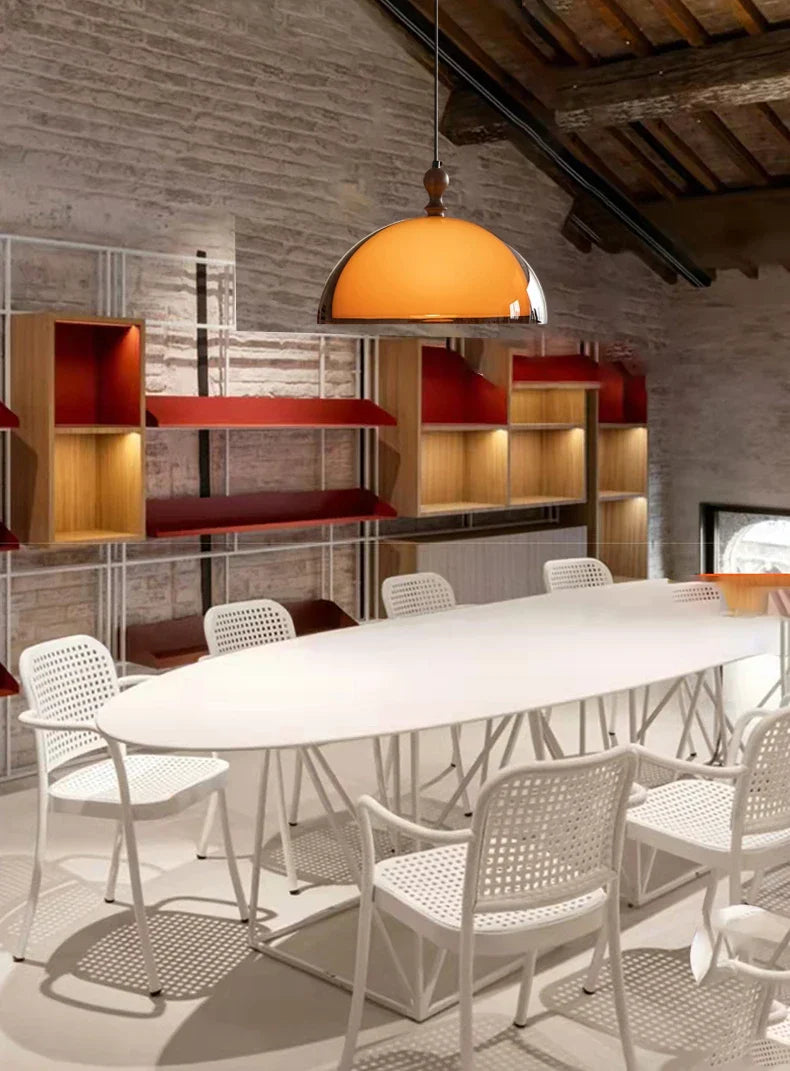 Warm amber acrylic pendant light with dark wood lampshade and polished metal fixture hanging above table
