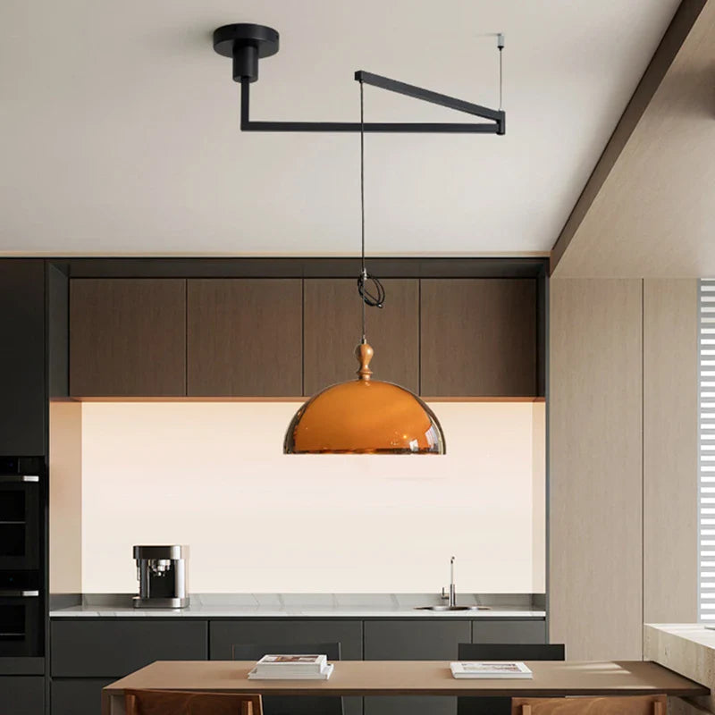 Acrylic pendant light with a sleek amber glass shade and polished brass fixture on a dark wood lampshade arm
