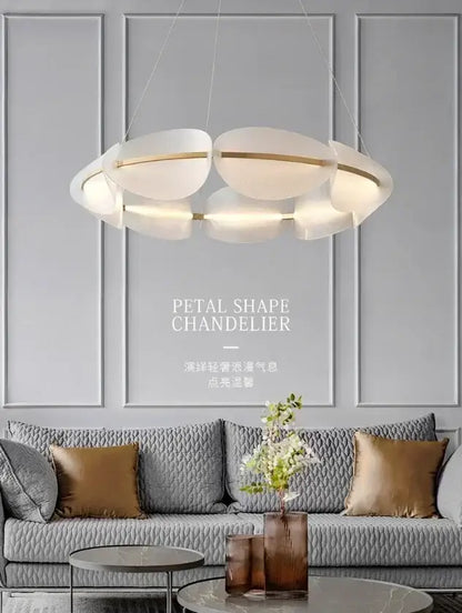 Modern white acrylic ring chandelier with gold accents hanging above a gray sofa in a dining room setting