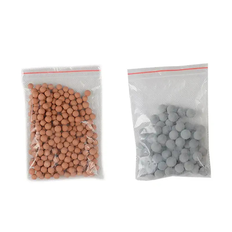 Two clear plastic bags with tan and gray filter beads for adjustable high pressure shower head use