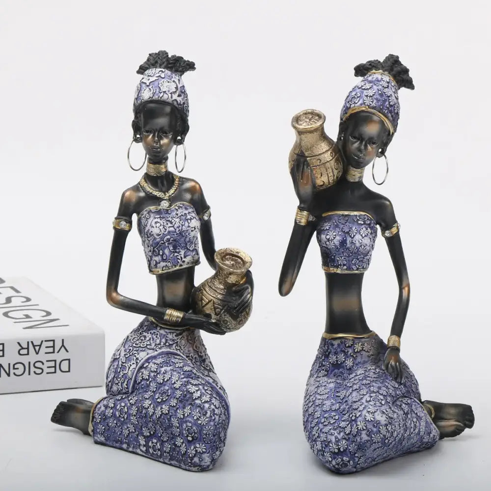 Two african woman sculptures dressed in purple and gold holding ceramic jugs for decorbites african woman decor