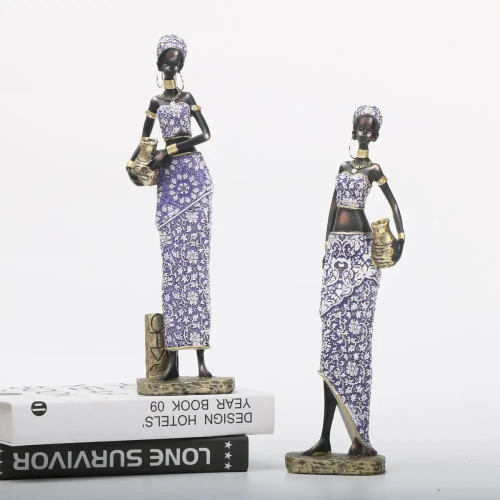 Two african woman sculptures in purple and gold patterned garments ideal for decorbites african woman decor