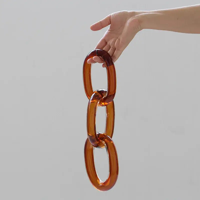 A hand holds a chunky amber-colored acrylic glass handcrafted chain buckle for living room decorbites decor