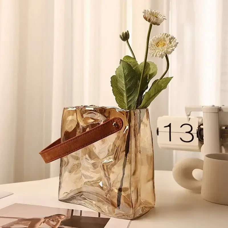 Translucent amber bag shape glass vase with crinkled texture and brown leather handle for living room decor